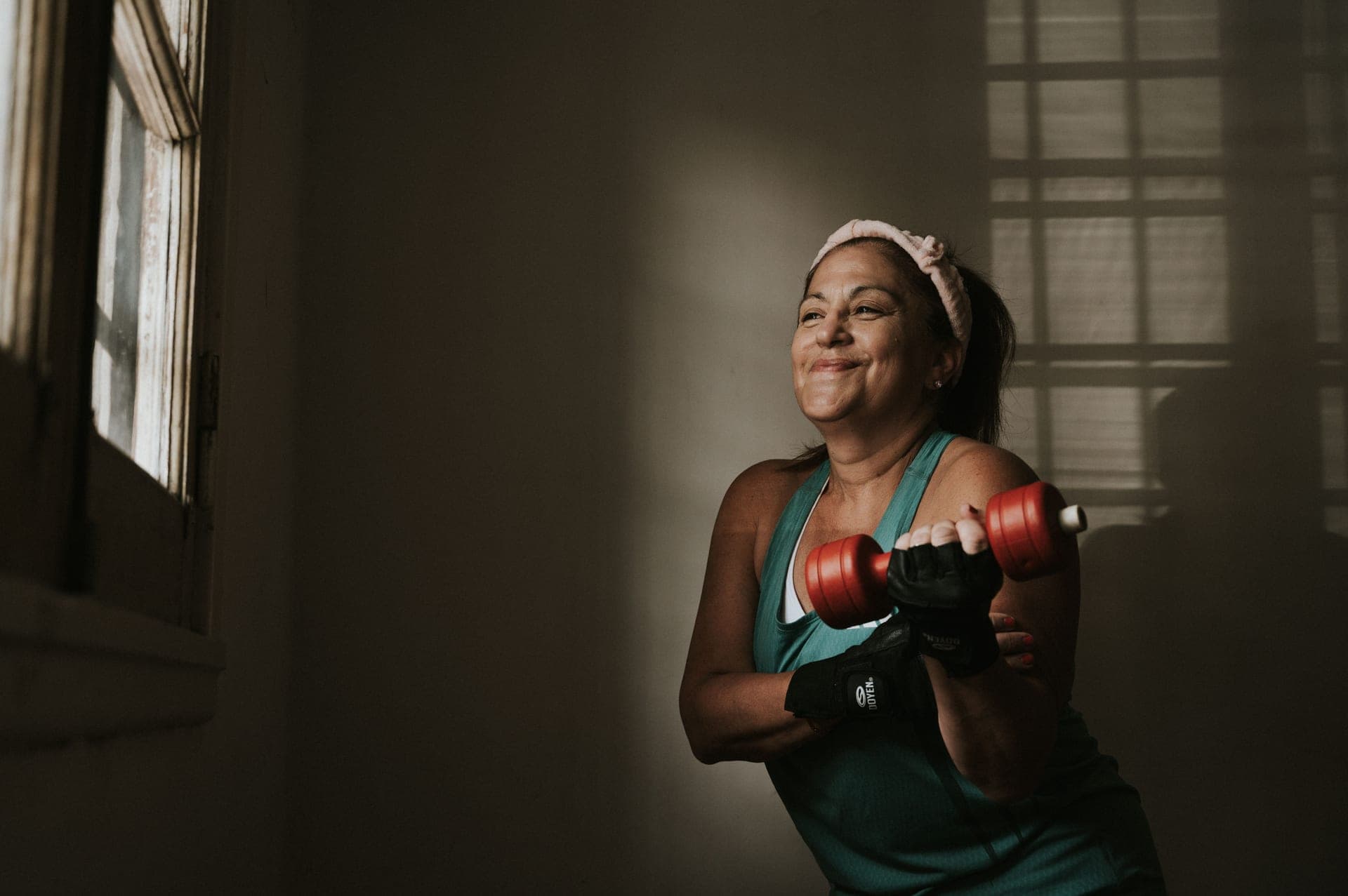 Middle-aged woman smiling while exercising with dumbbells indoors