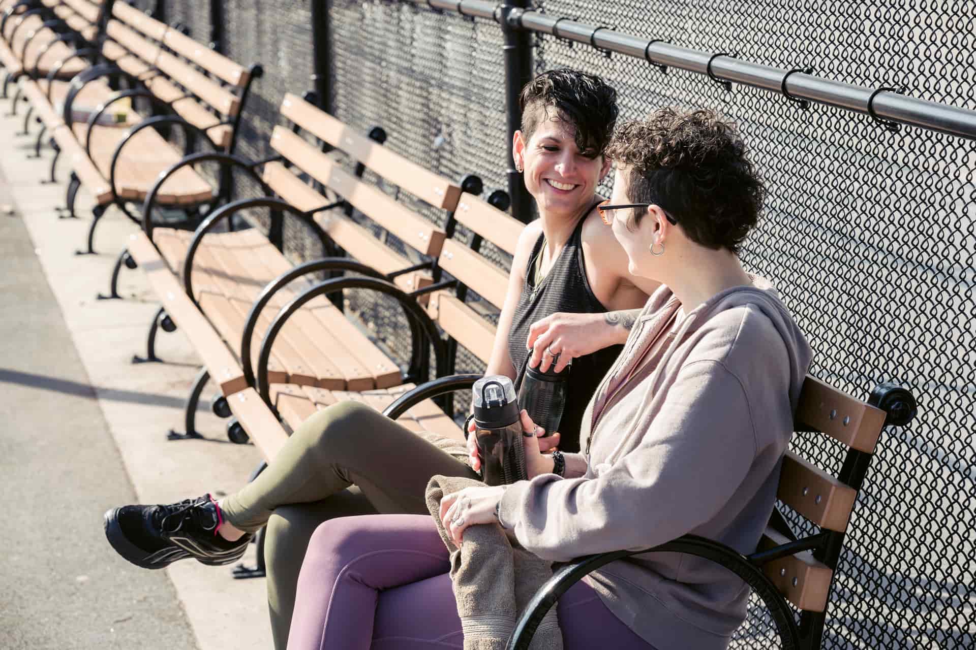 Two women talking on a park bench after a workout