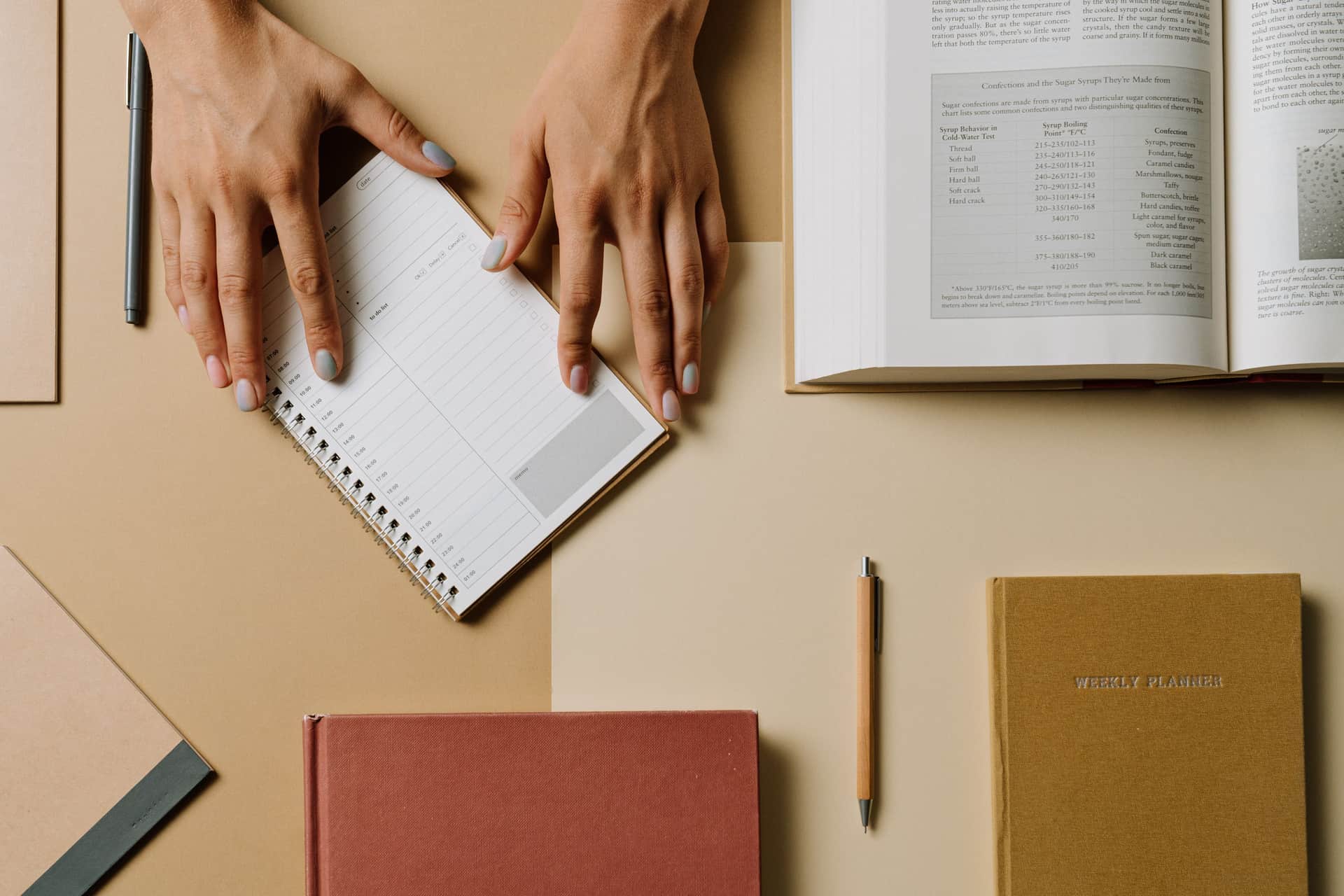 Overhead view of a weekly planner and notebooks on a desk