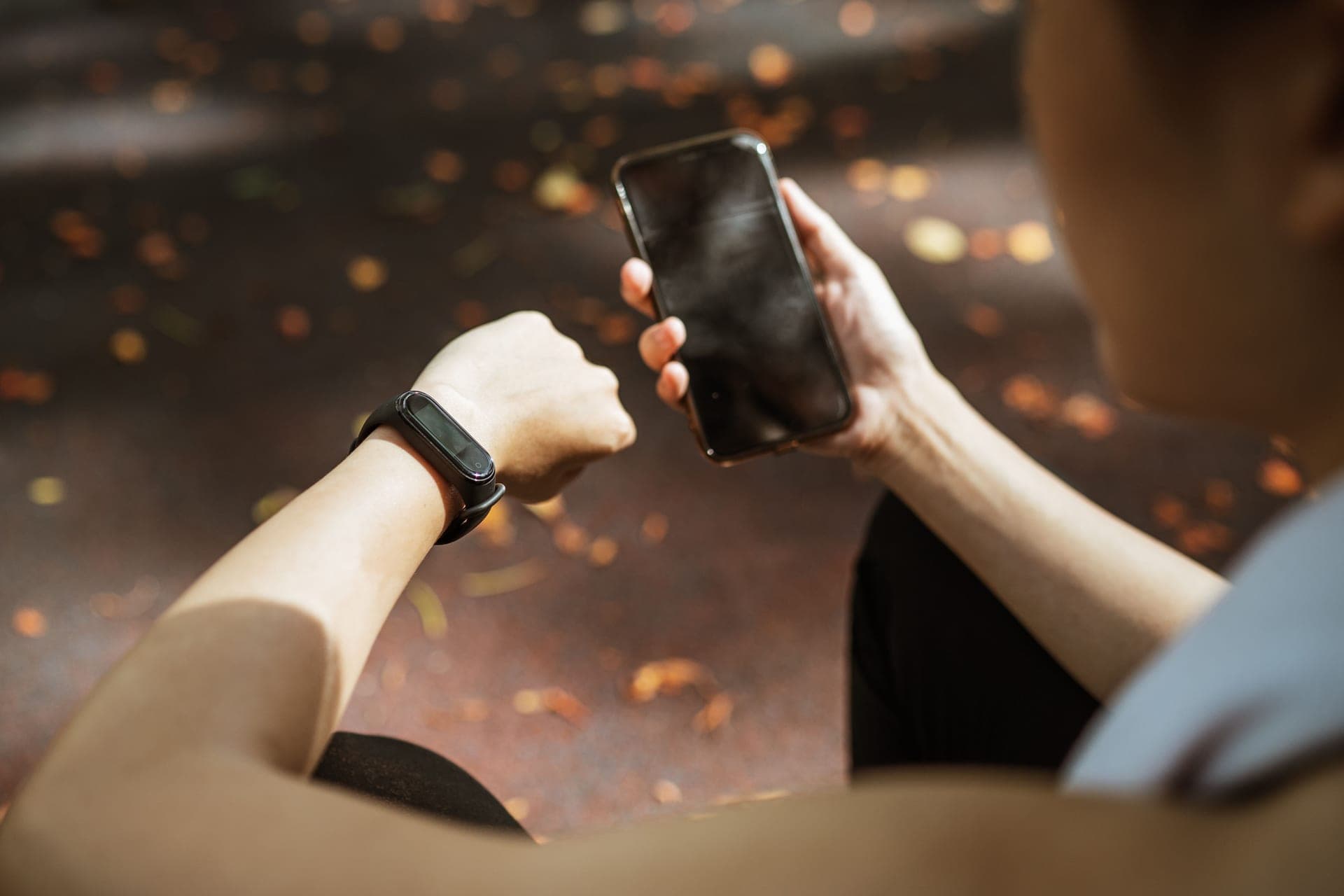 Woman checking a fitness tracker on her wrist while holding a phone