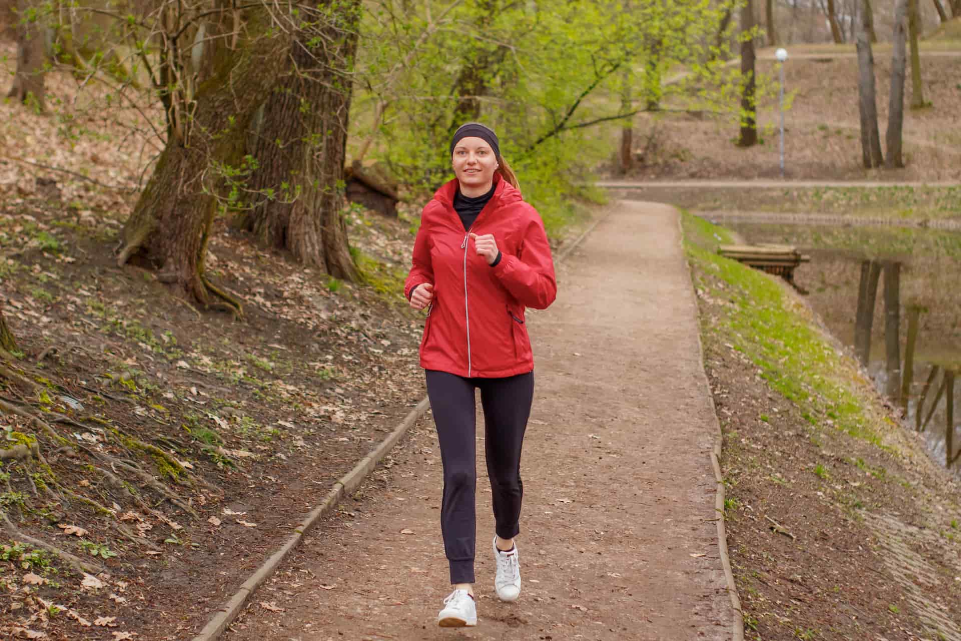 Woman jogging on a wooded park trail in the morning