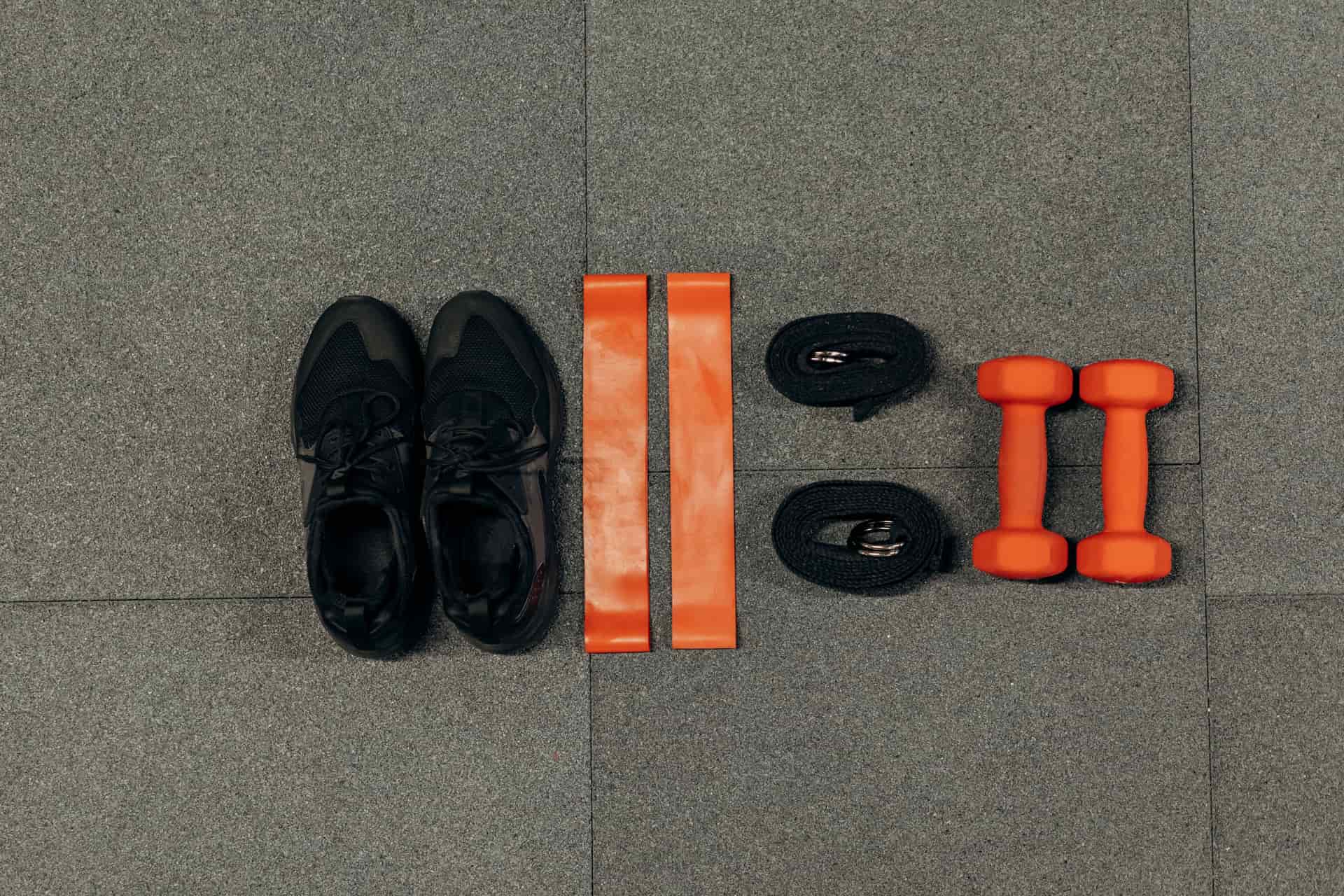Sneakers, resistance bands, and dumbbells laid out on a floor