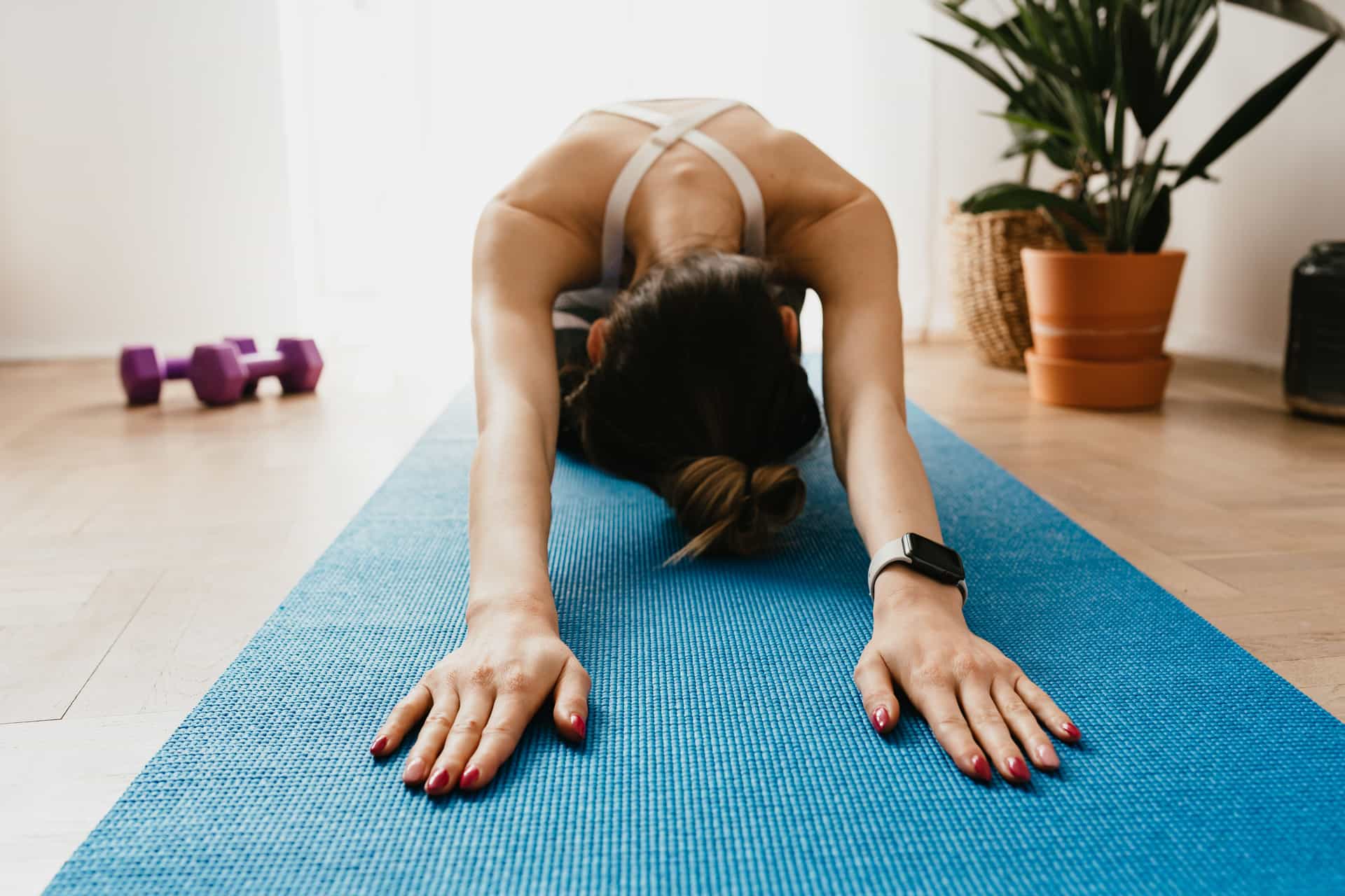 Woman resting in a gentle stretch on a yoga mat in a sunny living room